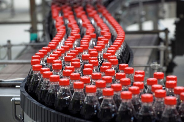 Image of cola bottles being processed along a production line - This image is used by Patient Guard to describe Quality Control.