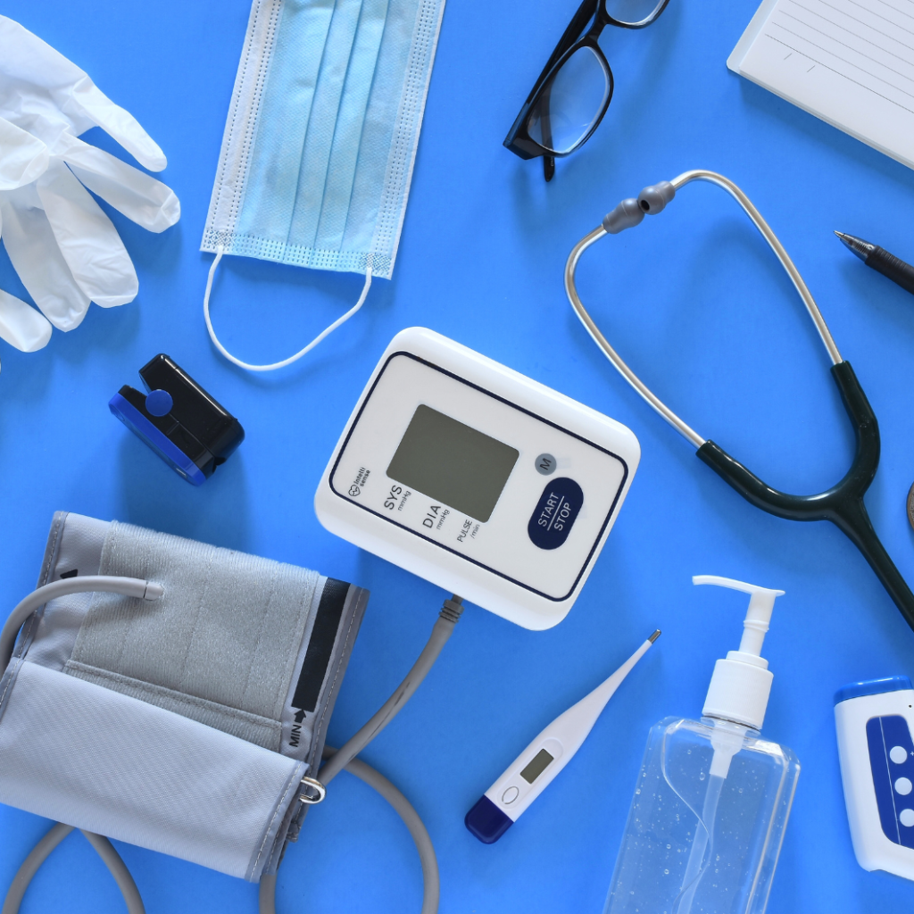 Image shoes stethoscope, blood pressure cuff, hand gel, digital thermometer, clip, glasses and rubber gloves on a dark blue background - This image is used by Patient Guard to represent its medical device and IVD regulatory and quality assurance related content.