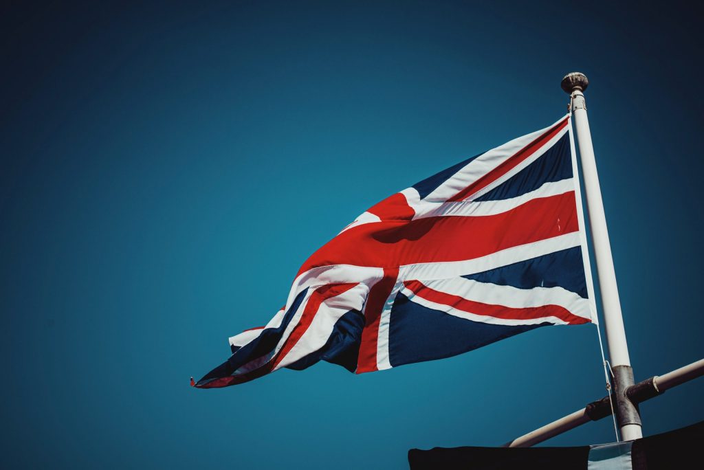 Image of the union jack (UK flag) on a flag pole with a blue sky background - used by patient guard to represent their UK related medical device and IVD consultancy services